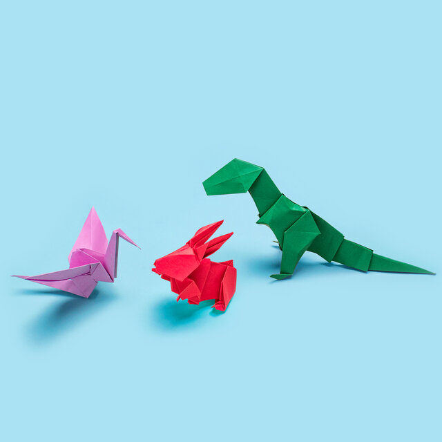 Drei Origami Dinosaurier auf blauem Hintergrund