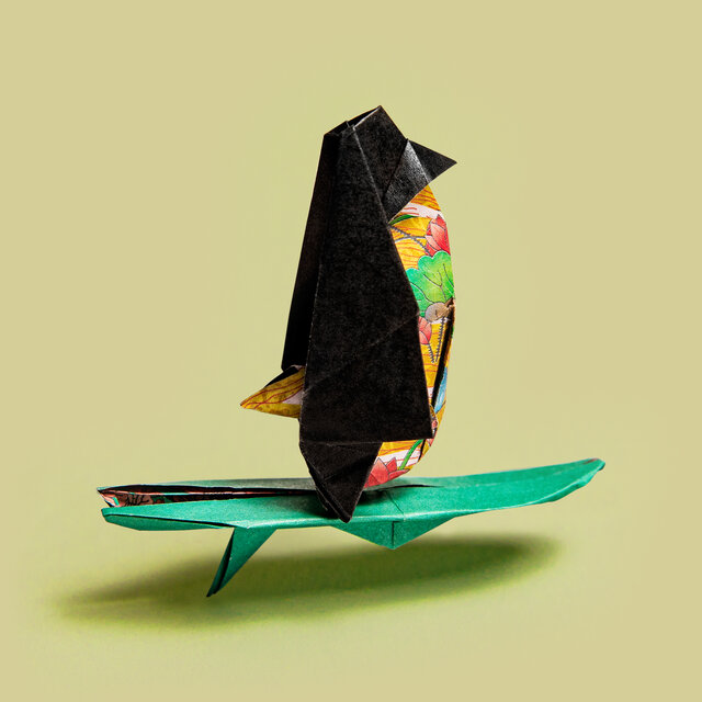 Origami Pinguin auf einem Surfbrett