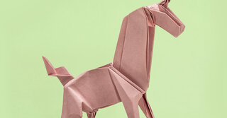 Origami eines Einhorns vor gr&uuml;nem Hintergrund