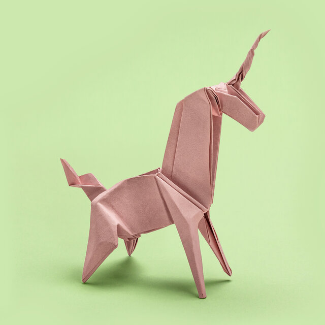Origami of a unicorn on green background