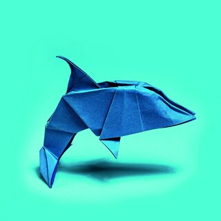 Blue origami dolphin on turquoise background
