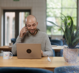 Image of a person talking on the phone while working on a laptop