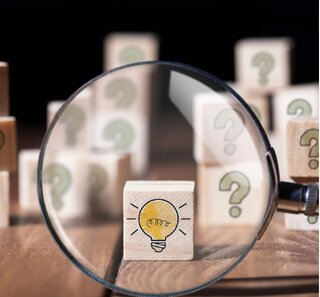 Image of a cube with a light bulb on it, viewed through a magnifying glass